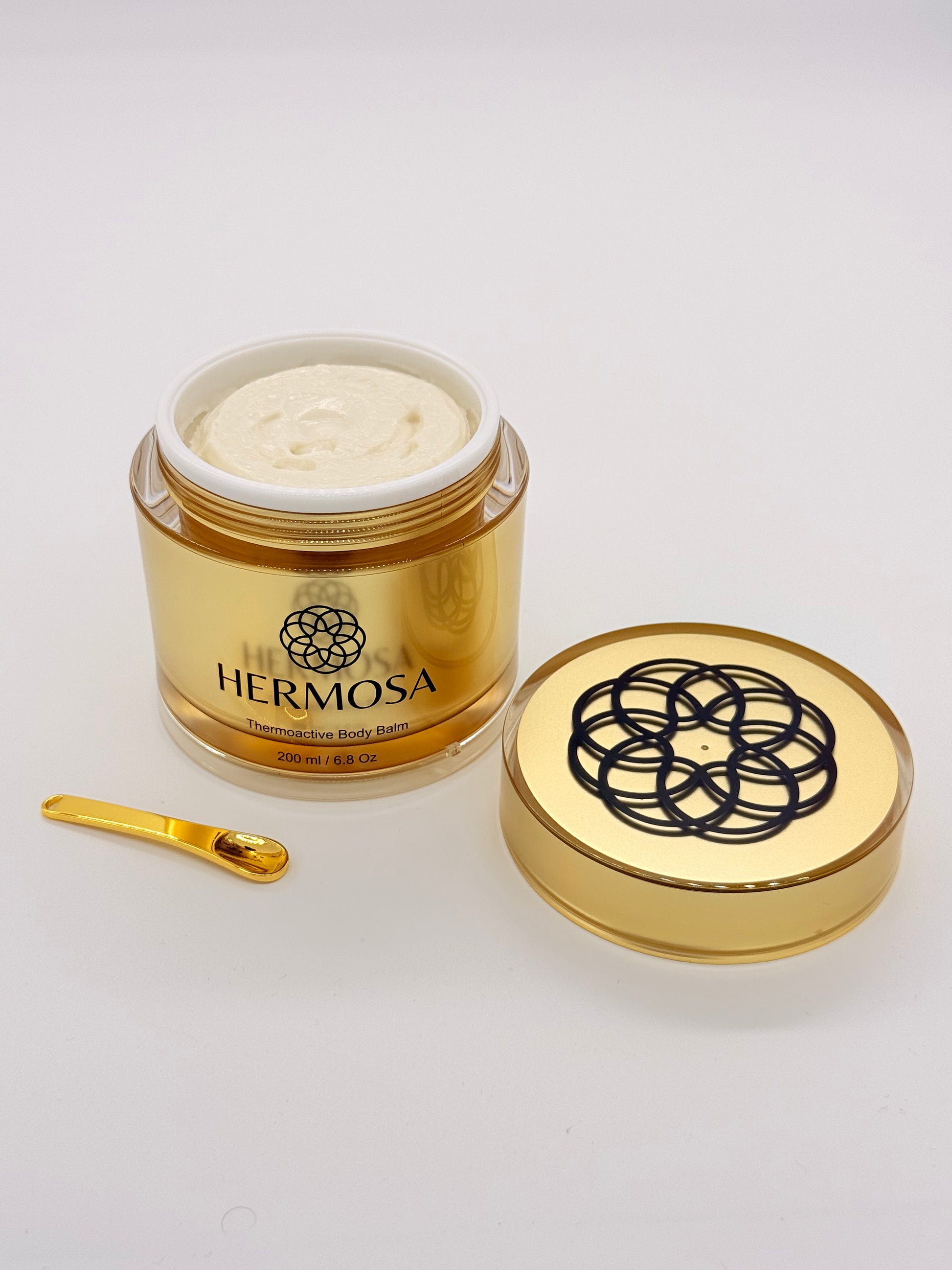 Otwarte opakowanie Hermosa Thermoactive Balm - struktura balsamu i złota łyżeczka
